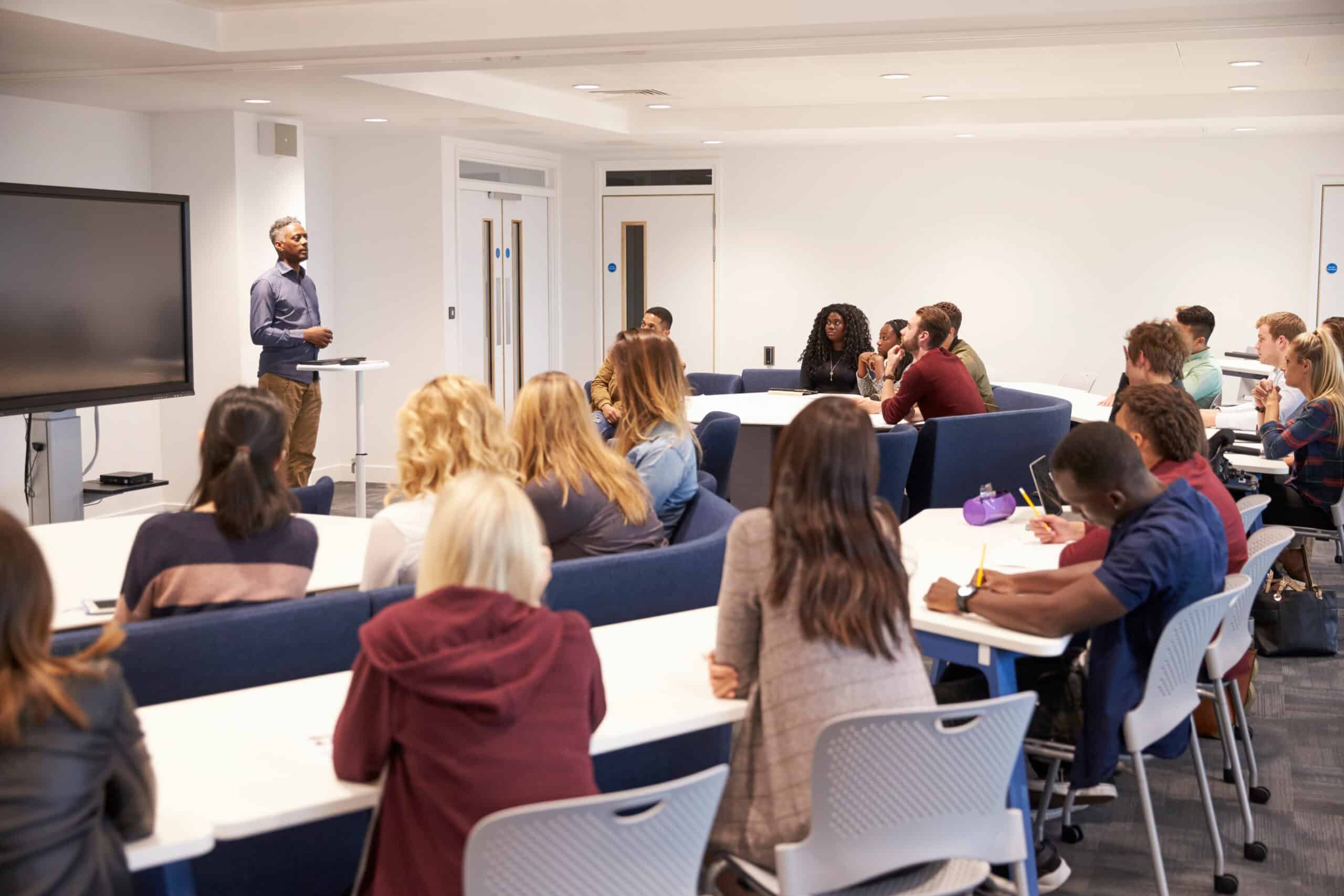 A presentation being given from a lectern in a classroom full of people