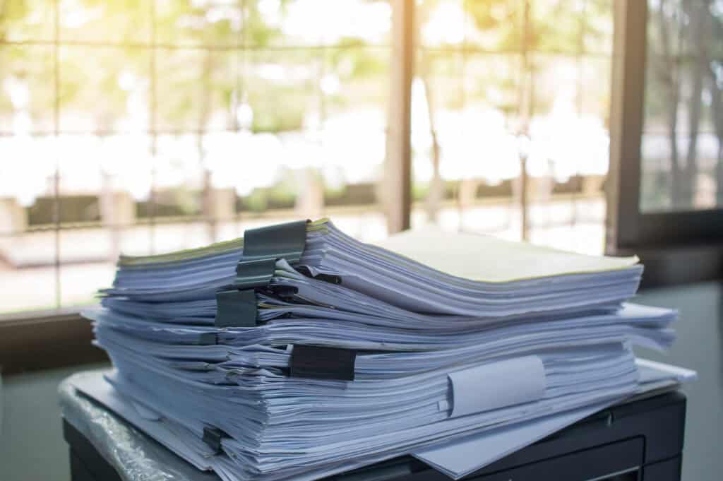 A stack of papers sitting on top of a desk in binder clips