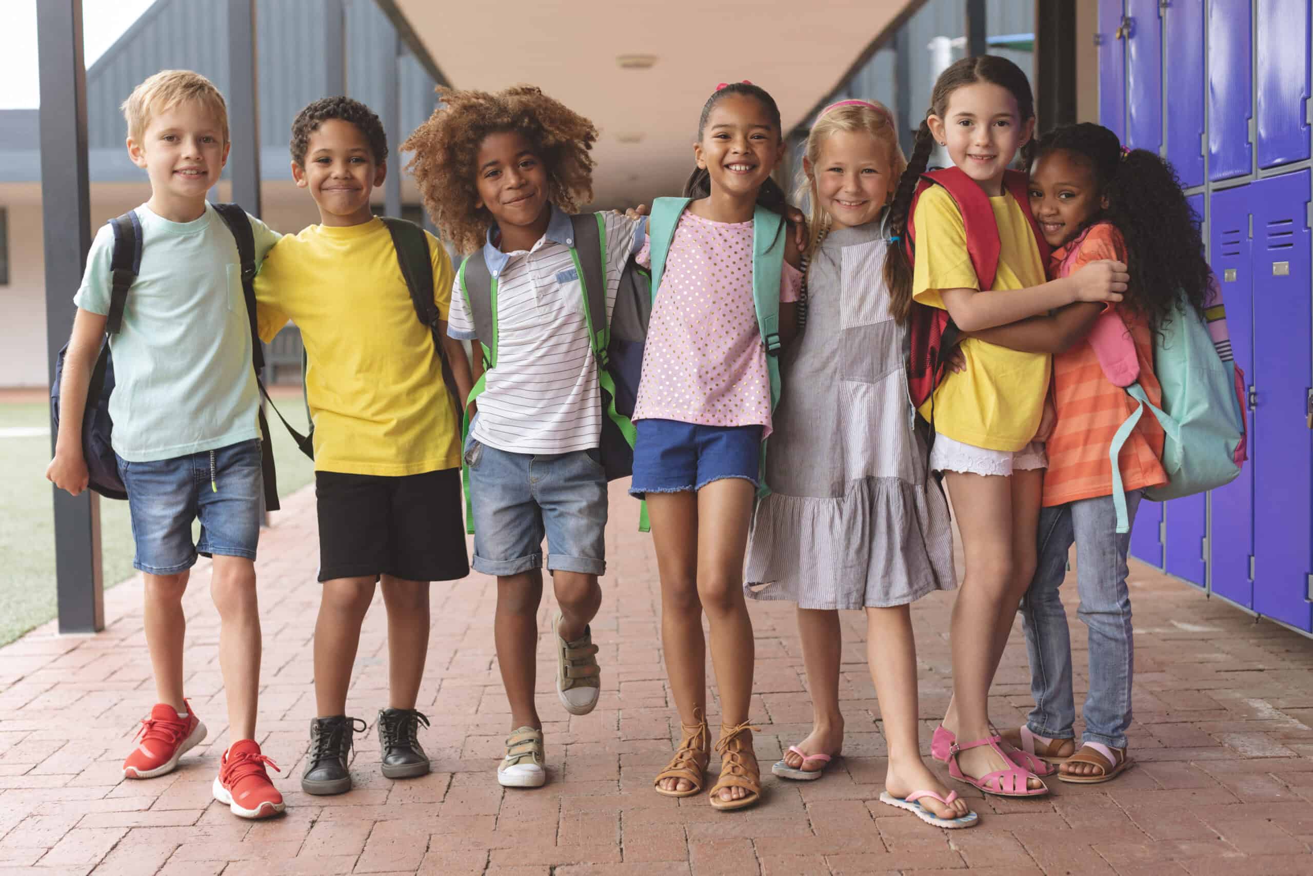 A group of children pose for a photo next to purple lockers in a school setting