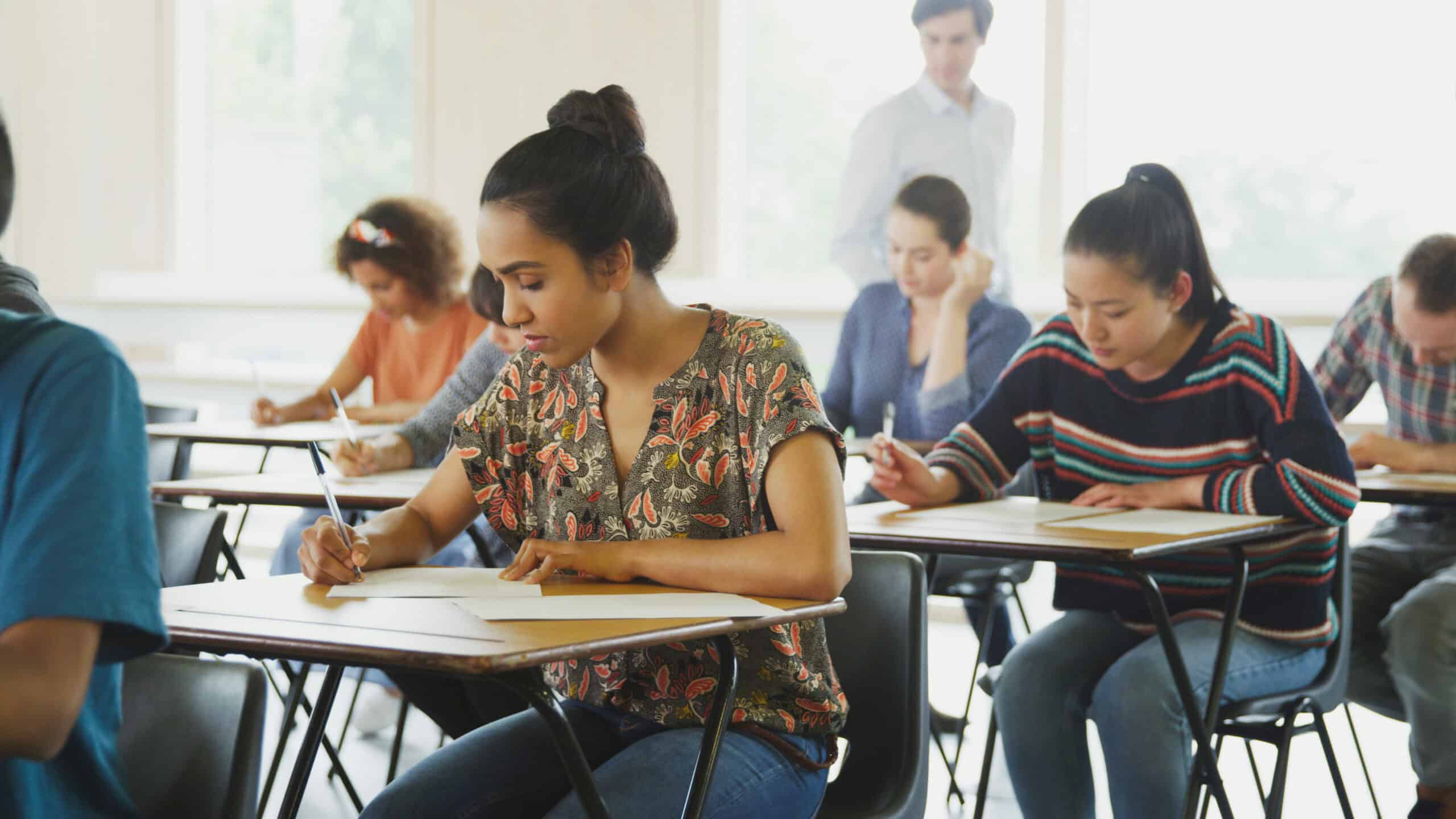 College students sitting at desks taking an exam in a classroom setting