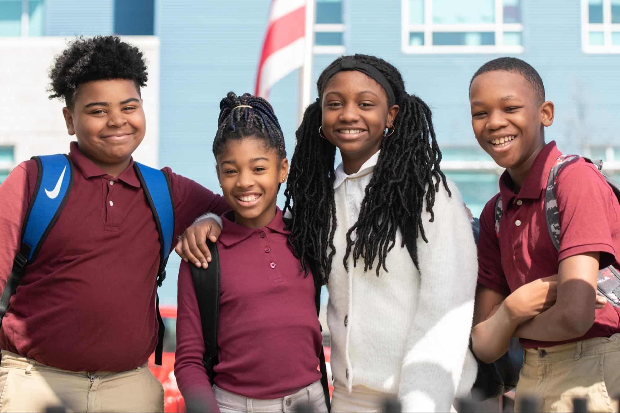 A group of four children smiling as their photo is taken